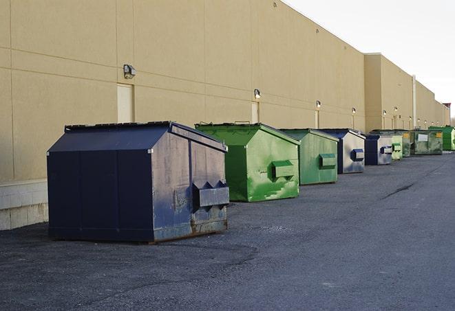 a construction worker unloading debris into a blue dumpster in Beardstown IL